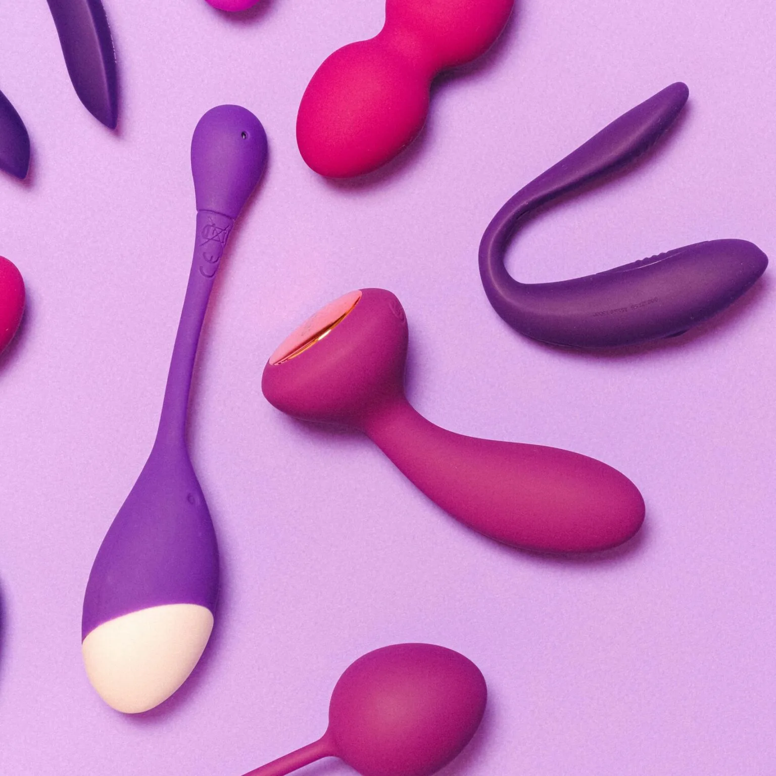 A variety of colorful silicone sex toys on a purple background showcasing modern pleasure products.