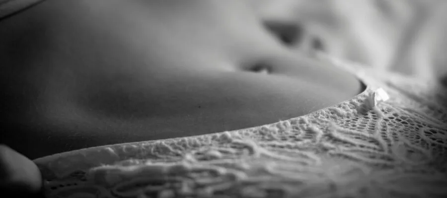 Artistic black and white close-up shot of lace lingerie on skin, highlighting texture and elegance.